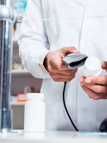 Pharmacist in white coat scanning barcode on pill bottle, ensuring accurate medication dispensing in a modern pharmacy setting.